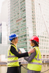 Portrait of two young, successful women architects who stand together and keep the folder with some documents in hands and discuss about new project, outdoors