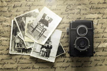 Studio shot of old vintage photo camera with pictures on wooden background