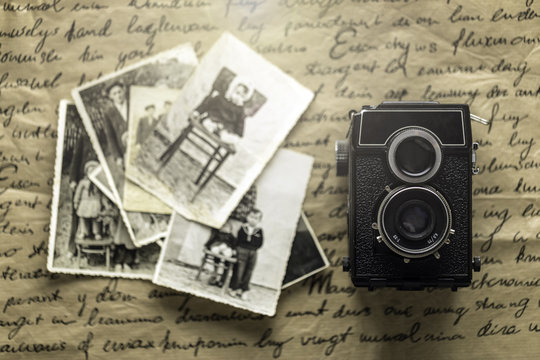 Studio shot of old vintage photo camera with pictures on wooden background