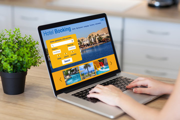 woman hands in laptop with hotel booking screen in room