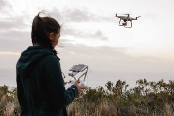 Woman watching and navigating a flying drone
