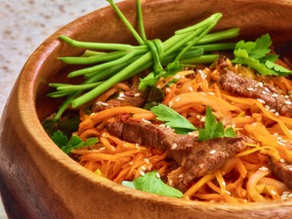 Asian Food: beef slices with carrot and fresh parsley  on a wooden plate
