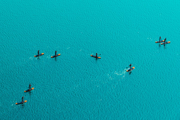 Aerial view of unrecognizable people stand up paddle boarding