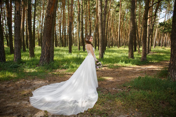 Beautiful bride in wedding dress in forest after wedding ceremony