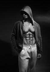 Naklejka na ściany i meble Portrait of strong healthy handsome Athletic Man Fitness Model posing near dark gray wall