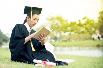 Graduate reading diary, notebook in her hand feeling relaxing and so happiness in commencement day