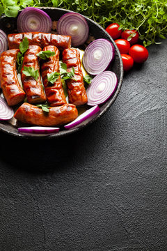 Grilled sausage, herbs and vegetables on black table