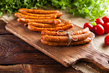 Raw sausage, tomato and fresh herbs on wooden and canvas background