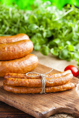 Raw sausage, tomato and fresh herbs on wooden and canvas background