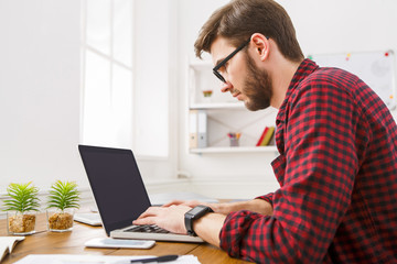 Young businessman working with laptop in modern white office