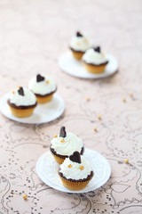 Chocolate Vanilla Mini Cupcakes decorated with chocolate hearts on white plates, on light beige background.