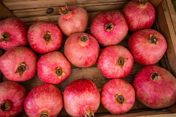 Fototapeta na wymiar Pomegranates in a box. Pomegranate background. Top view.