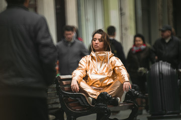 People pass the woman in golden rain suit