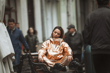 Woman in golden suit meditates on the bench