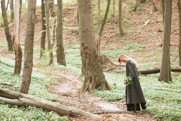 Woman walks with a bouquet across the forest