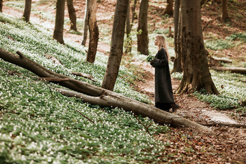 Woman walks with a bouquet across the forest