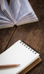 Blank notebook with book on wooden table