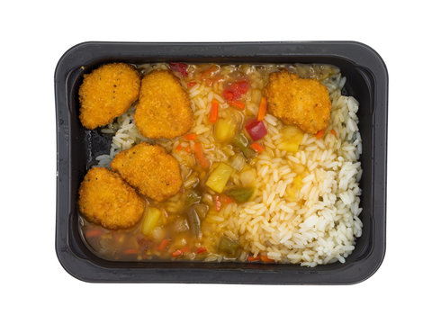 Top view of a sweet and sour chicken TV dinner in a black microwavable tray isolated on a white background.