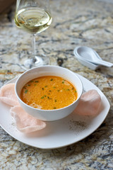 Creamy crab soup served with crab chips and glass of white wine on marble backround