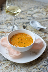 Creamy crab soup served with crab chips and glass of white wine on marble backround