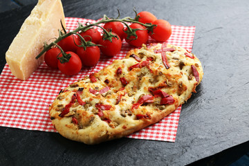 Hot pizza slice with melting cheese on a rustic wooden table.