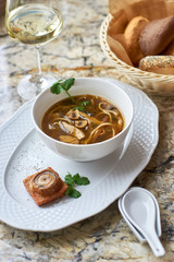 Asian cuisine. Mushroom soup with egg noodles served with toast, bread and white wine on marble background.