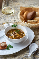 Asian cuisine. Mushroom soup with egg noodles served with toast, bread and white wine on marble background.
