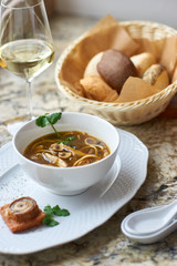 Asian cuisine. Mushroom soup with egg noodles served with toast, bread and white wine on marble background.
