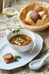 Asian cuisine. Mushroom soup with egg noodles served with toast, bread and white wine on marble background.