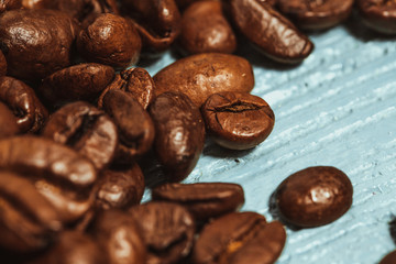 Dark many roasted coffee beans on blue background