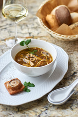 Asian cuisine. Mushroom soup with egg noodles served with toast, bread and white wine on marble background.