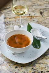 Japanese cuisine. Miso soup in white ceramic bowl served with green leaf, sppon and glass of white wine on marble table.