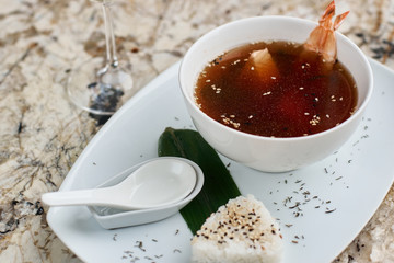 Japanese cuisine. Suimono or Matsutake soup served in white ceramic plate with spoon, rice and white wine on marble background.
