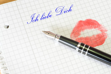Ein Abdruck vom roten Lippen auf einem Brief und ein Text Ich liebe Dich