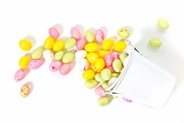 Pastel color jelly beans (egg shape for easter) candy in white bucket on white background
