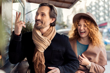 Cheerful couple is ready to drink something on street