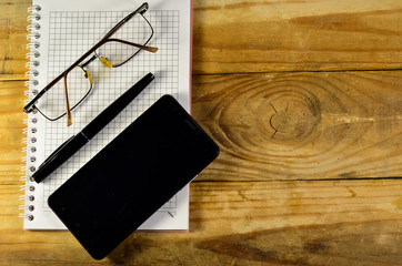 Fountain pen, smartphone and glasses on the notebook