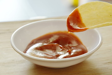crispy and salt potato chips on dish dipping with tomato sauce