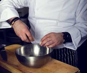 The chef of the restaurant breaks the egg into a metal bowl, filtered foto