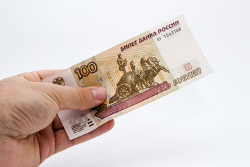 A close up photo of a Caucasian male hand holding a 100 russian ruble note