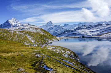 Mountain with snow and green grass with reflection in the lake, Autumn daylight, Switzerland