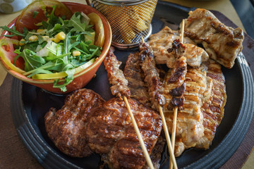 Close up of mixed grilled meat Beef, pork, poultry with grilled garlic, chili pepper and vegetable salad