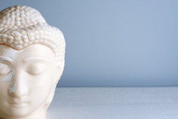 Buddha face. Buddha statue made of white marble with free space for text. Concept of peace, calm and tranquility. Buddhist artifact for Zen style interior decor. - Powered by Adobe