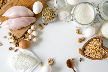 Fototapeta na wymiar Food full of proteins on white table. Milk, sour cream, cheese, chicken fillet eggs mushrooms, Lentils and peas and cottage cheese. Proteins concept. Copy space for text. Sport diet healthy lifestyle.