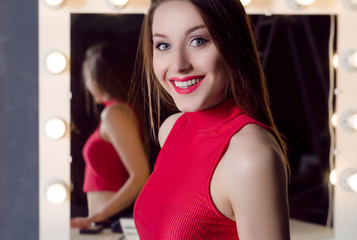 Portrait of young attractive woman with long hair in studio near the mirror