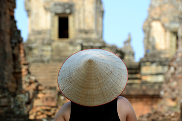 Rear View Of Person Wearing Asian Style Conical Hat Against Historic Temple