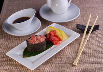 Sushi nigiri with spicy tuna fish served with chopsticks and soy sauce on table