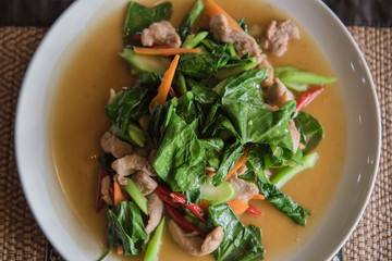 closeup fried kale with pork on a white plate . Thai food.