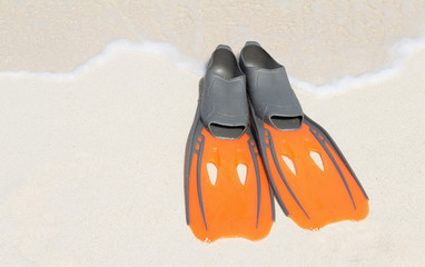 bright orange swimming flippers on the sandy beach