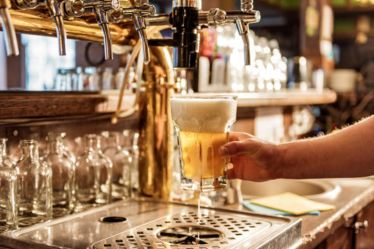 Male arm keeping pouring beer in alehouse